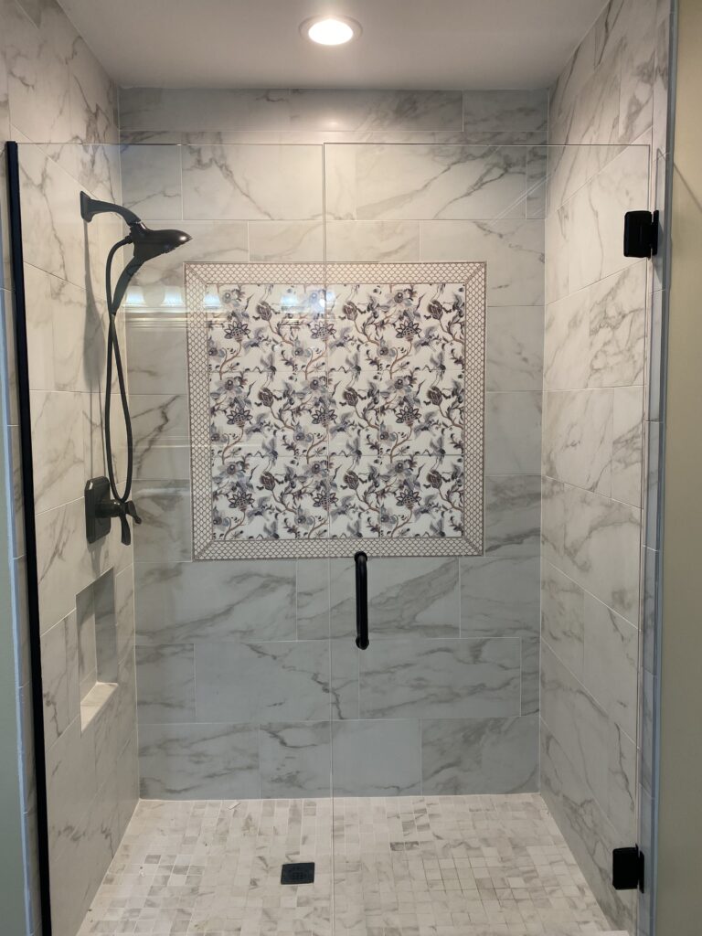 Marble shower with a floral feature tile wall by Palacios Installation