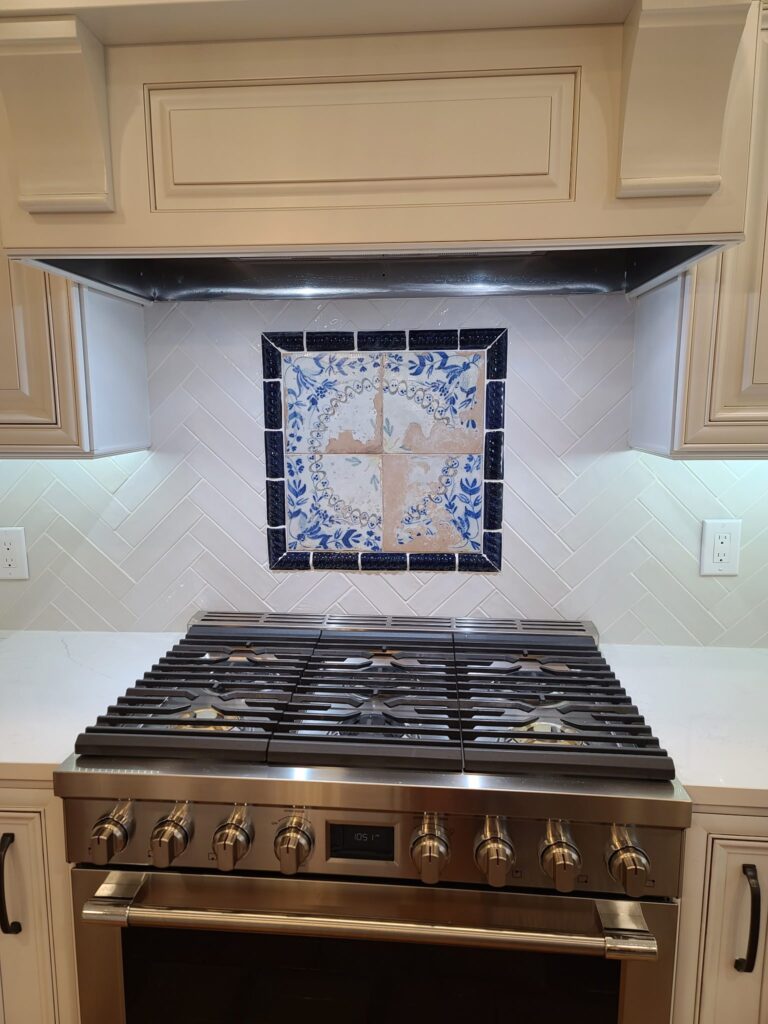 Herringbone backsplash with a decorative tile medallion behind the range, Calhoun, GA by Palacios Installation