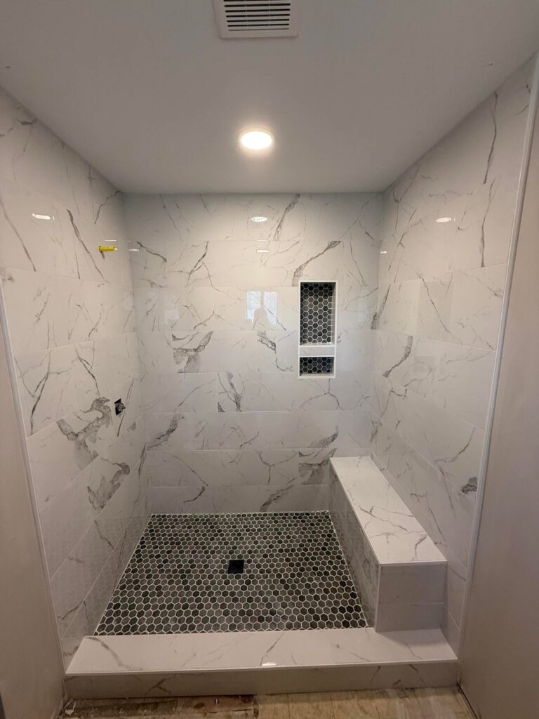 Marble-look tile shower with a built-in bench and hexagon floor, Chattanooga, TN by Palacios Installation